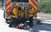 Firefighters on the tailboard during brush fire battle