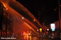 Firefighters train multiple hose streams on the flames