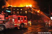 Fire truck in front of flames shooting from top of building