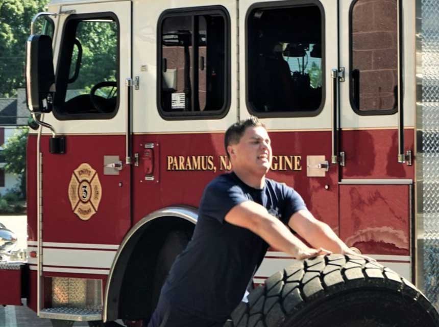 Firefighter rolling a tire in front of fire truck