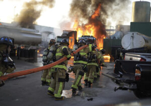 Miami Dade firefighters with hoseline and flames