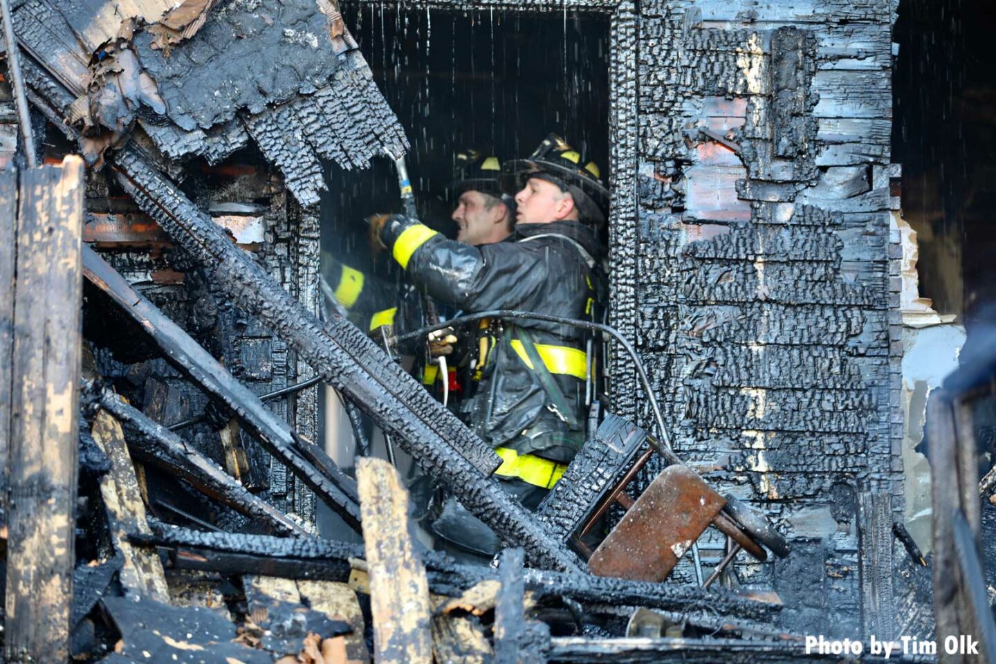 Chicago firefighters amidst charred remains of a home