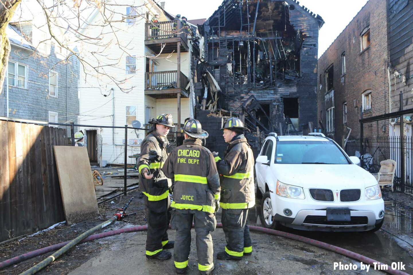 Chicago firefighters in the foreground with charred remains of a home in the background