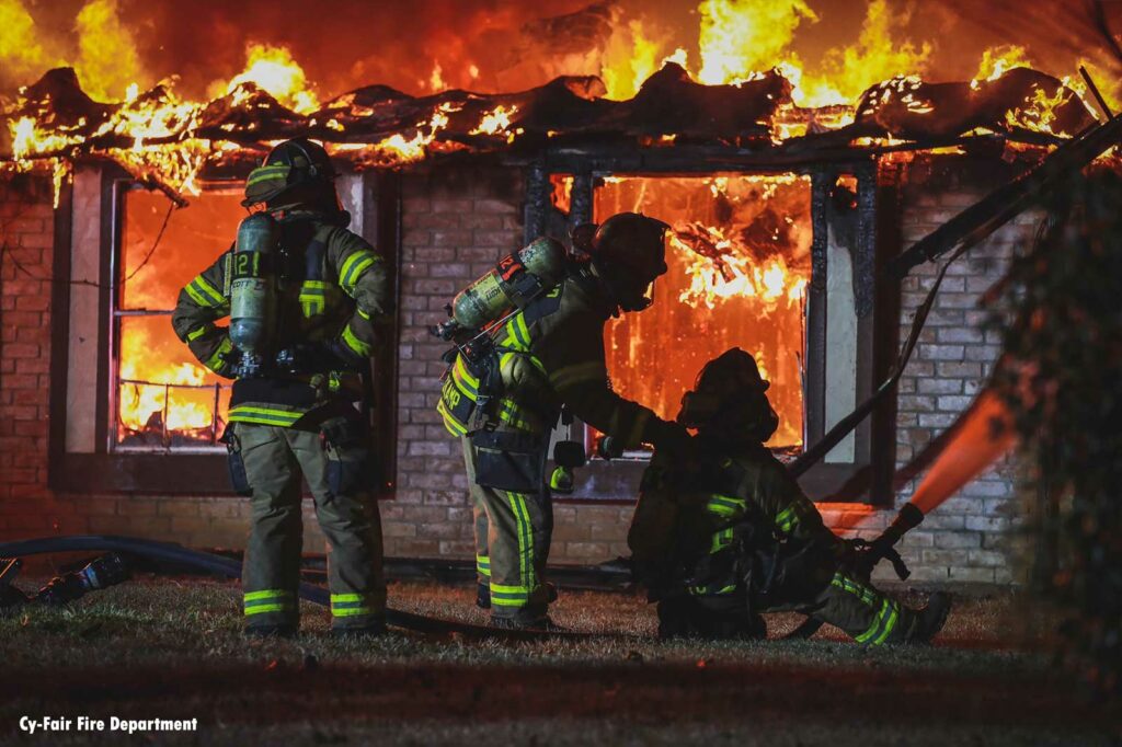 Firefighters add hose stream on the exterior of a house