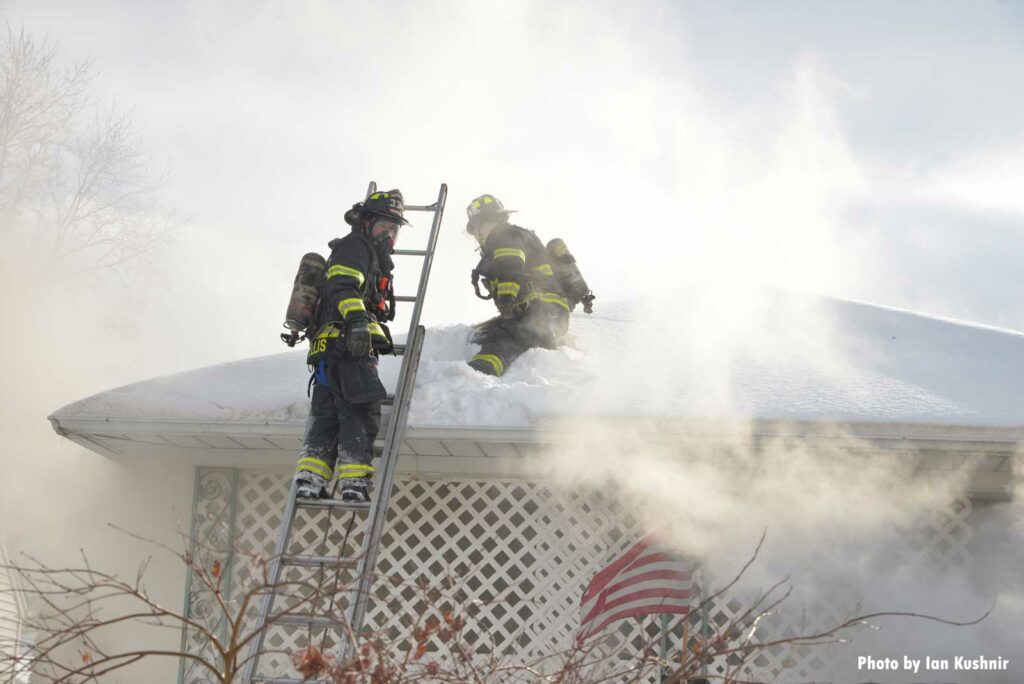 Firefighters working the roof at the house fire