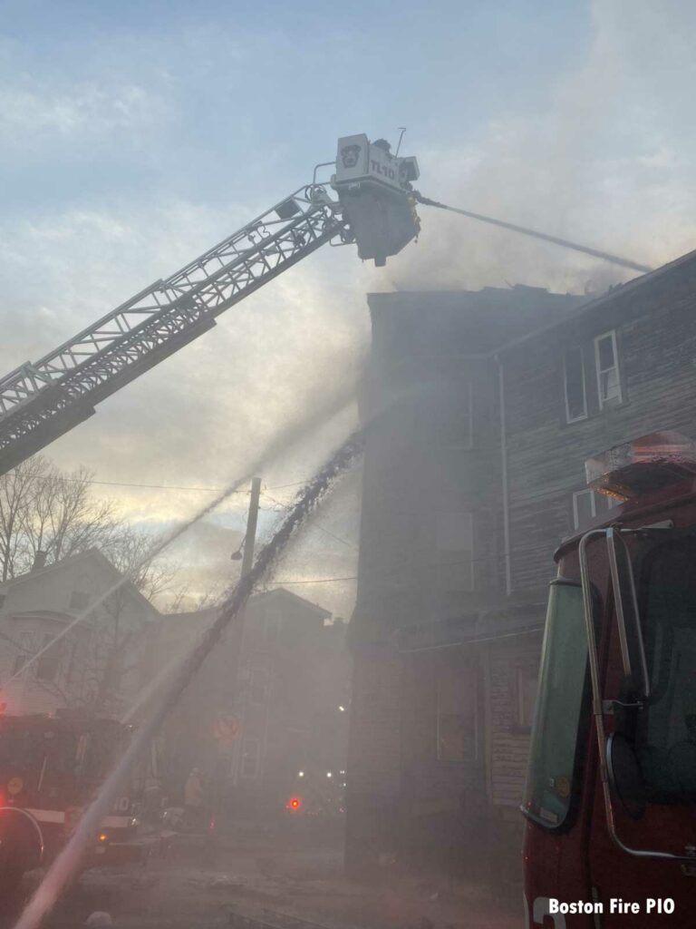 Boston tower ladder with firefighters in bucket directing stream