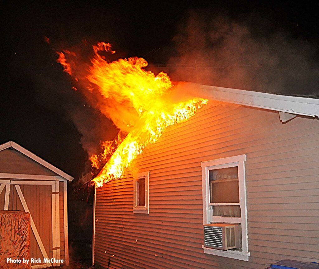 Flames rip along the roofline of a home