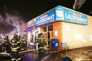 Firefighters, hoselines, and aerial device outside commercial building on Long Island