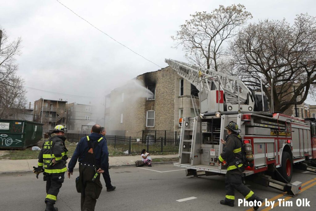 A Chicago Fire Department aerial device in use as water sprays from the interior of the building to the exterior