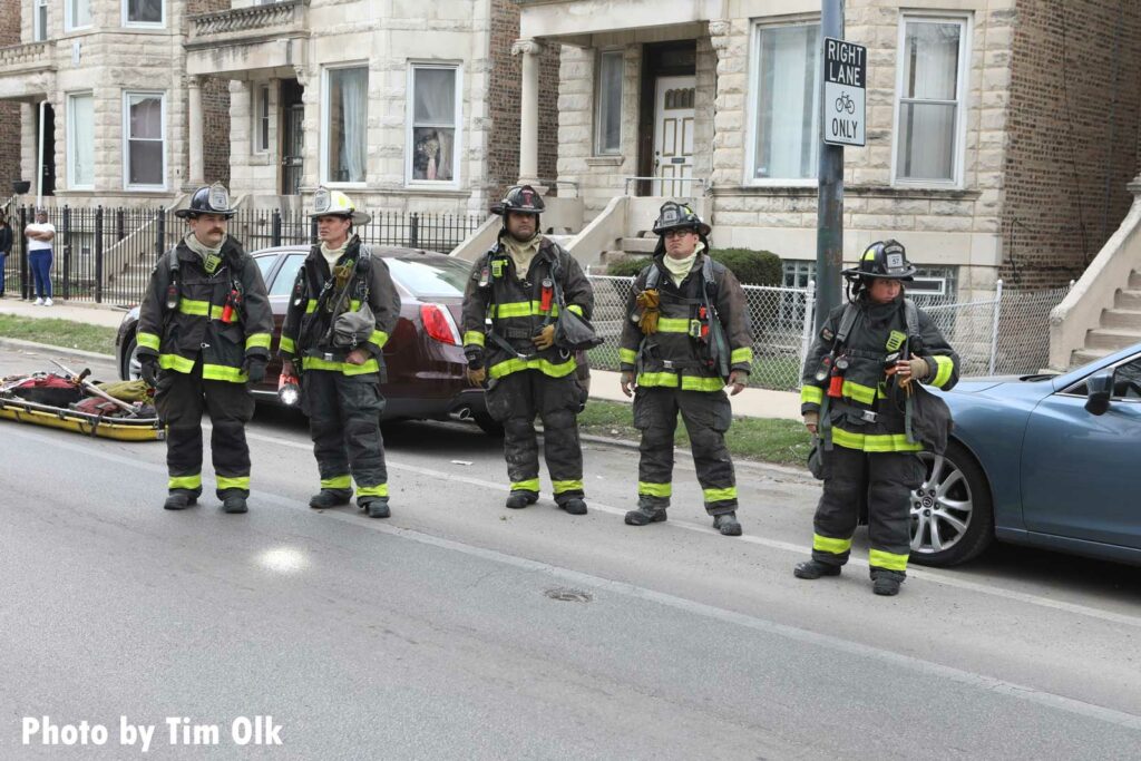 Five Chicago firefighters in full gear at the fire scene