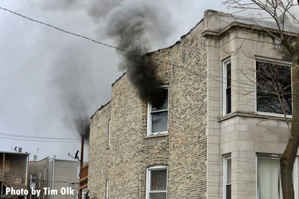 Black smoke shoots from a window and the rear of the building