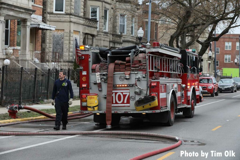 Firefighter with a section of LDH in front of a Chicago Fire Department fire apparatus