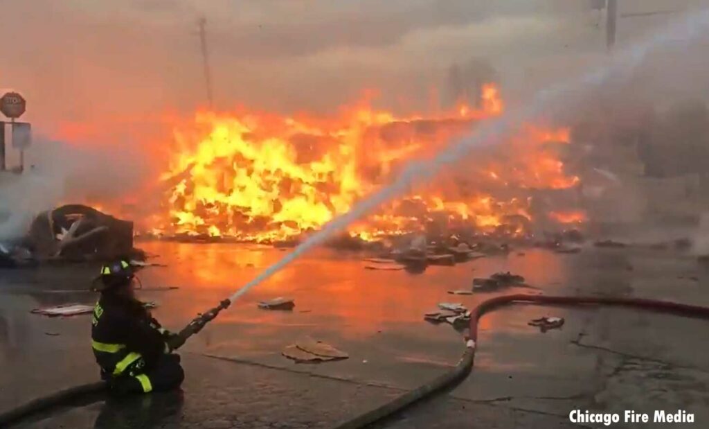 Chicago firefighter on hoseline sprays water on recycling center fire