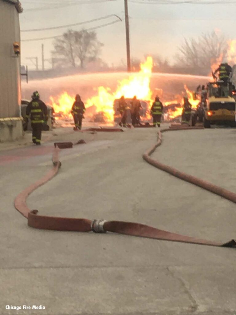 Hose and coupling with Chicago firefighters and flames in the distance