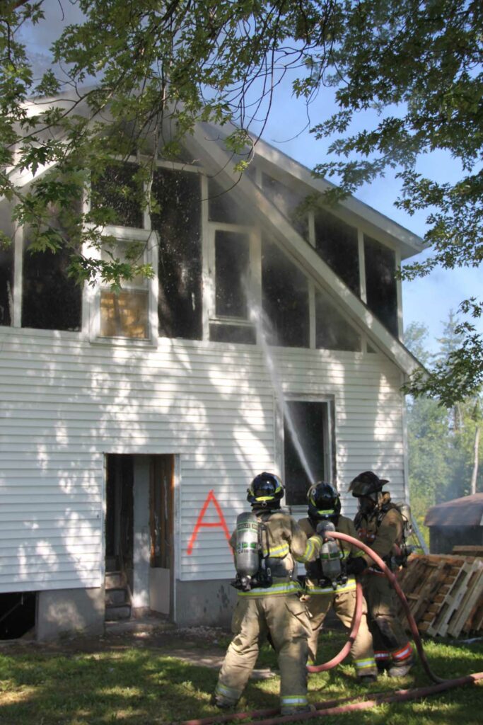 Firefighters train a hose stream on window