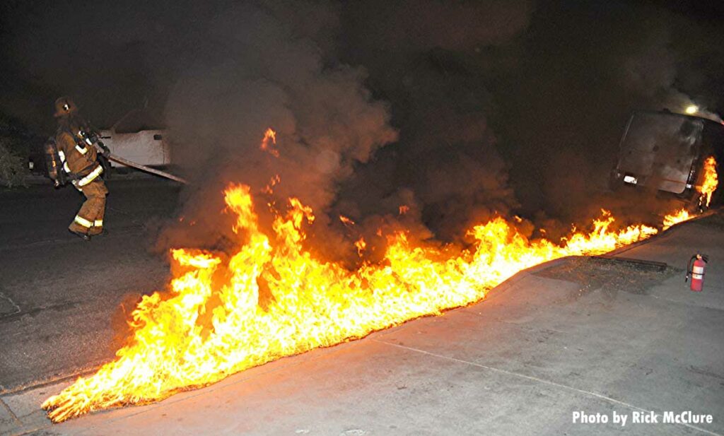 Flames race along flowing fuel from a vehicle fire