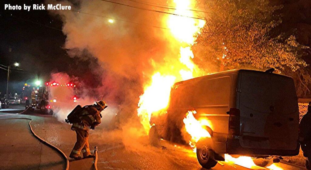 Firefighter puts water underneath a burning van