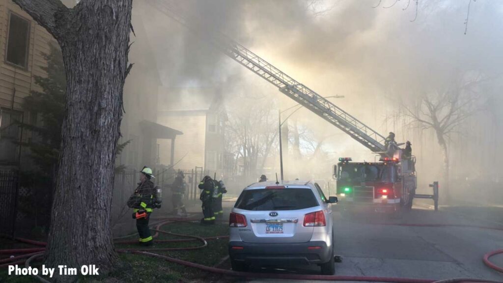 Chicago firefighters and an aerial ladder extended upward into smoke