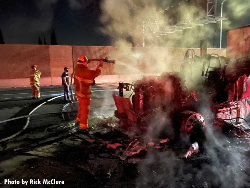 Firefighter pours water on burning tractor trailer on Los Angeles freeway