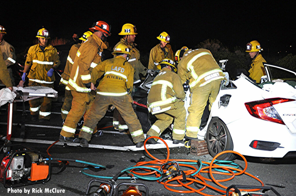 Firefighters work to remove a victim from a crash scene in Los Angeles