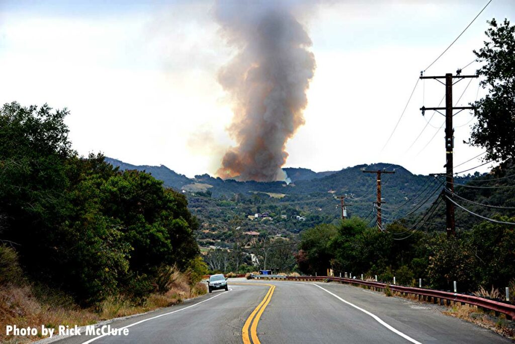 Smoke rises from the Palisades fire, as seen from a roadway