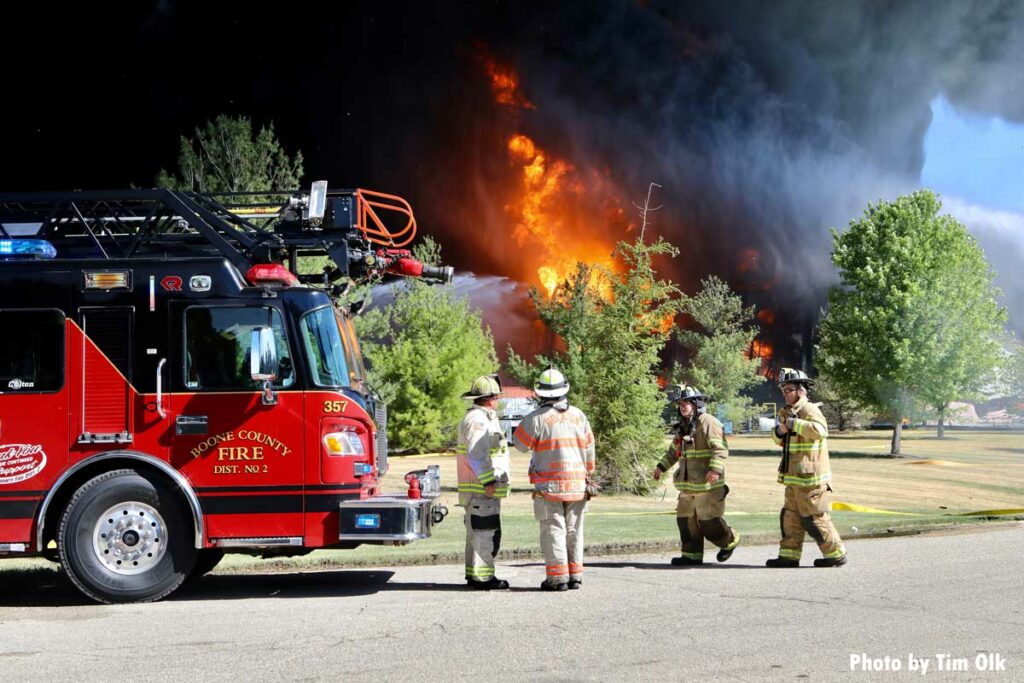 Firefighters with Boone County fire truck with flames and smoke in background