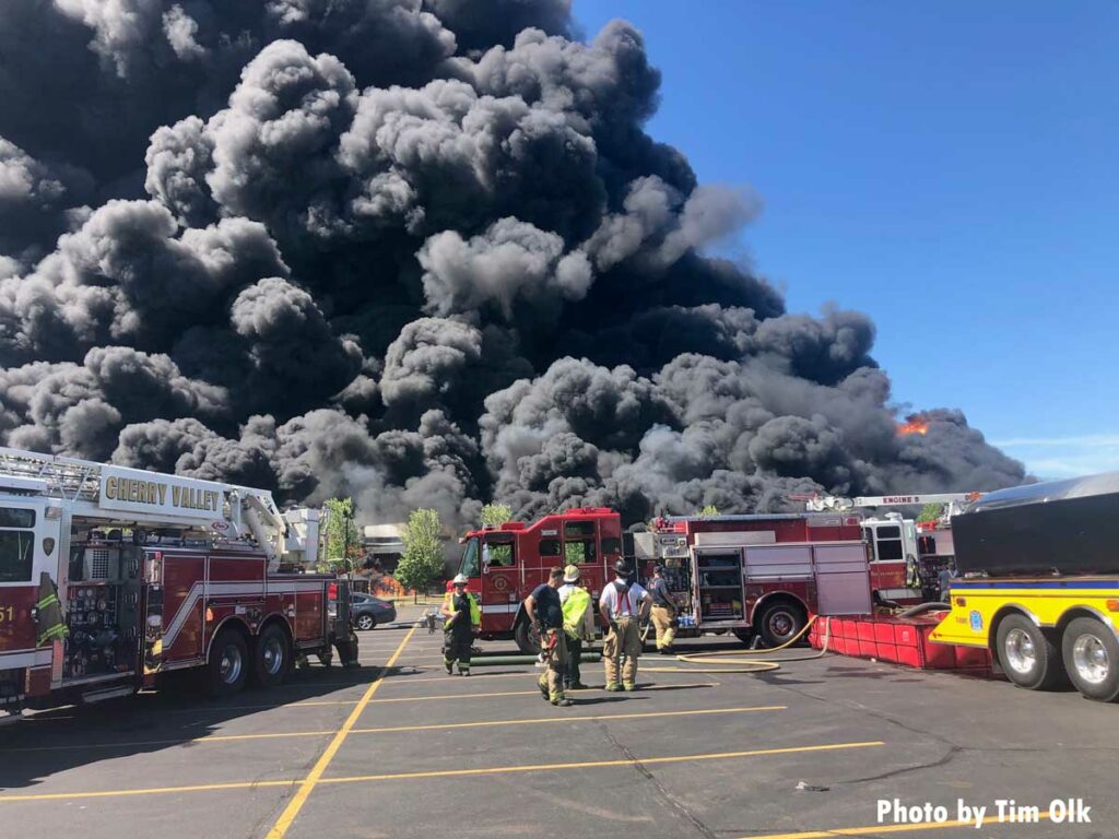 Giant plumes of smoke show the scale of the incident with fire trucks in foreground