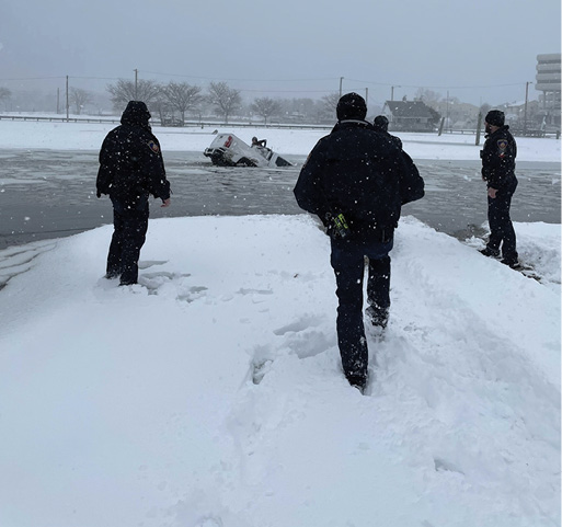 Two Stamford police officers (left and right) and Palmer arrive and make verbal contact with a female occupant (the driver) climbing out of the rear window.