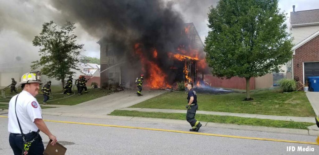 Firefighters put water on a burning home with roaring flames in Indianapolis, Indiana