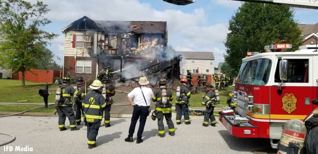 Indianapolis firefighters and fire truck outside a burned home