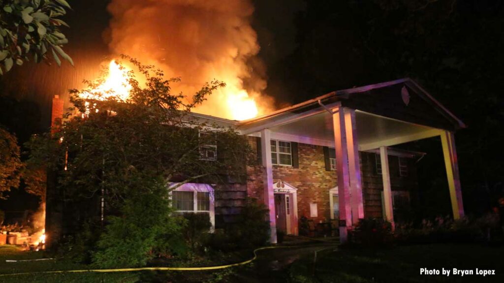 Flames pour from the roof of a Long Island home