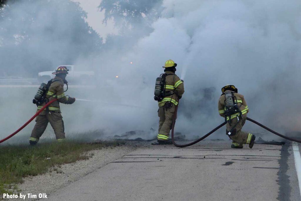 Firefighters maneuver two hoselines at the scene of a semi fire in Illinois