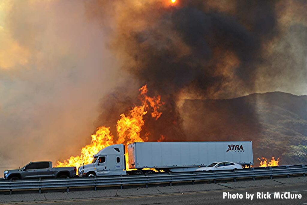 Tractor trailer drives past massive wildfire flames