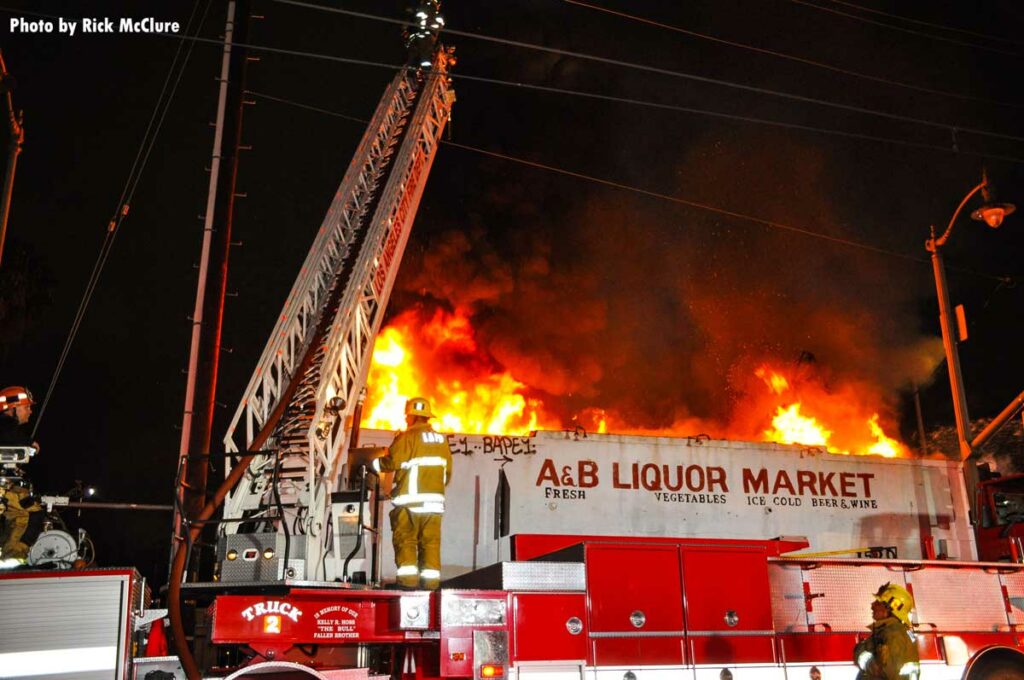 LAFD Truck 2 with aerial ladder extended as flames shoot from building