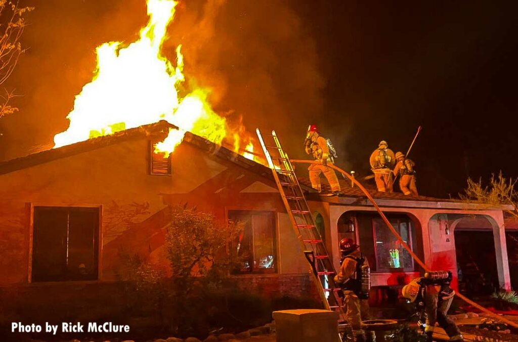 Firefighters lift hoseline to roof of home