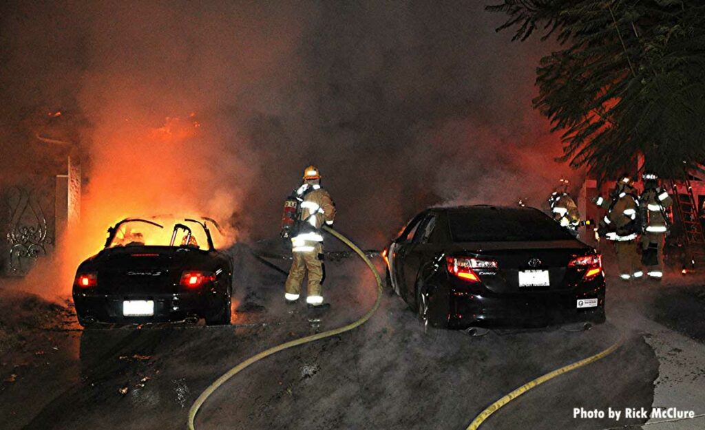 Firefighter in between two cars, one of them on fire