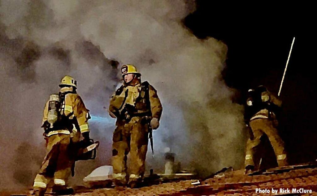 Three firefighters on the roof with smoke