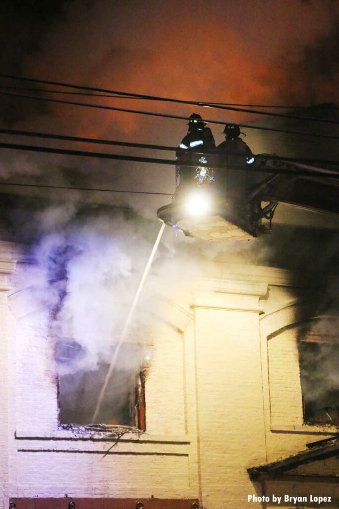 Firefighters in tower ladder bucket put water through window