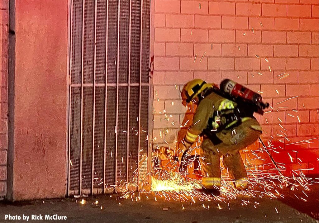 Firefighter with power saw cutting door at fire in Los Angeles