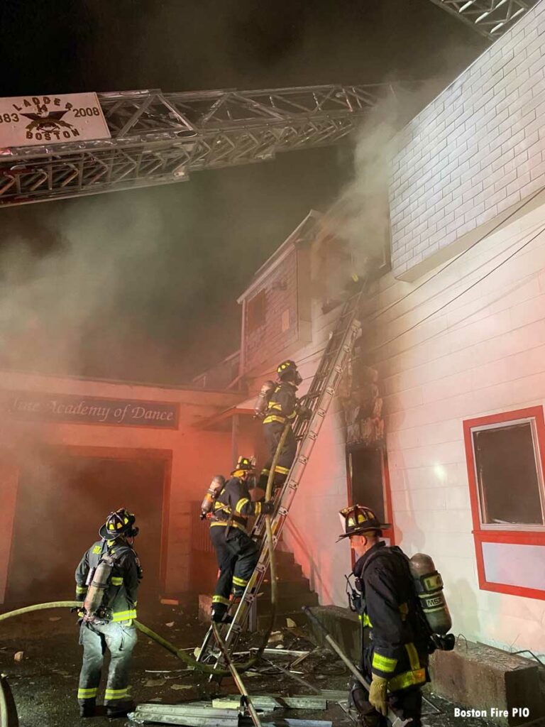 Firefighters scale ladder and aerial ladder at eight-alarm Boston fire