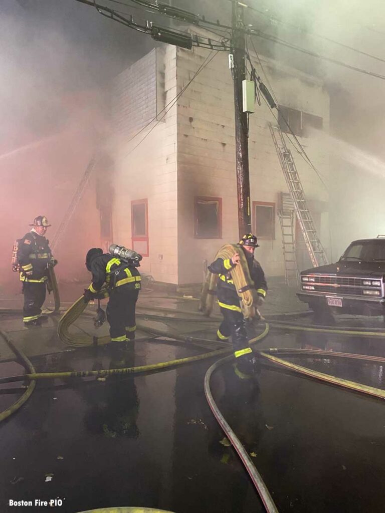 Firefighters haul hose at Boston fire