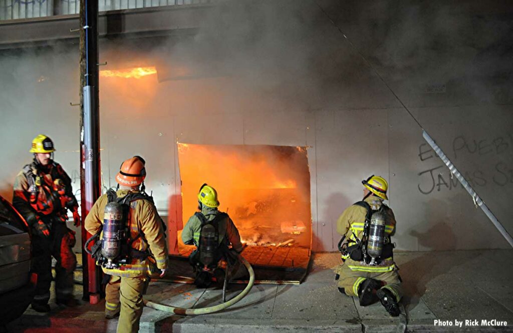 Hole cut through wall with firefighters and flames