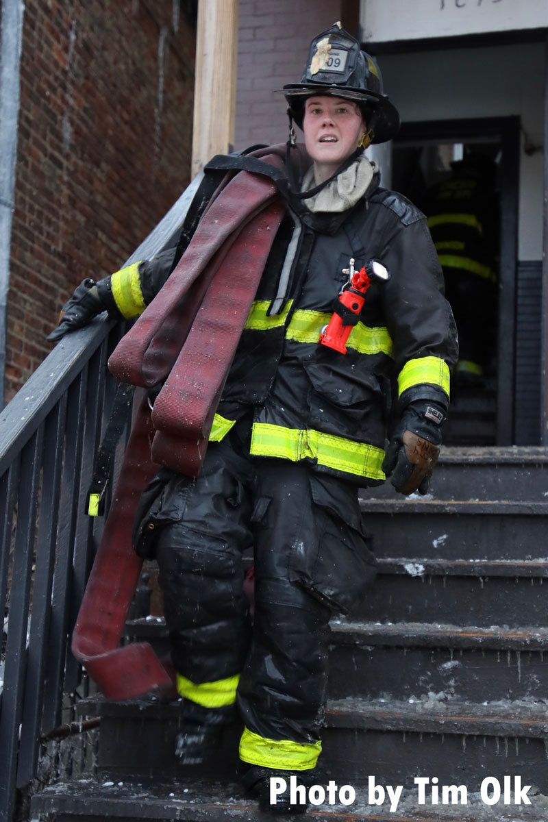 Chicago firefighter bearing hose on stairs