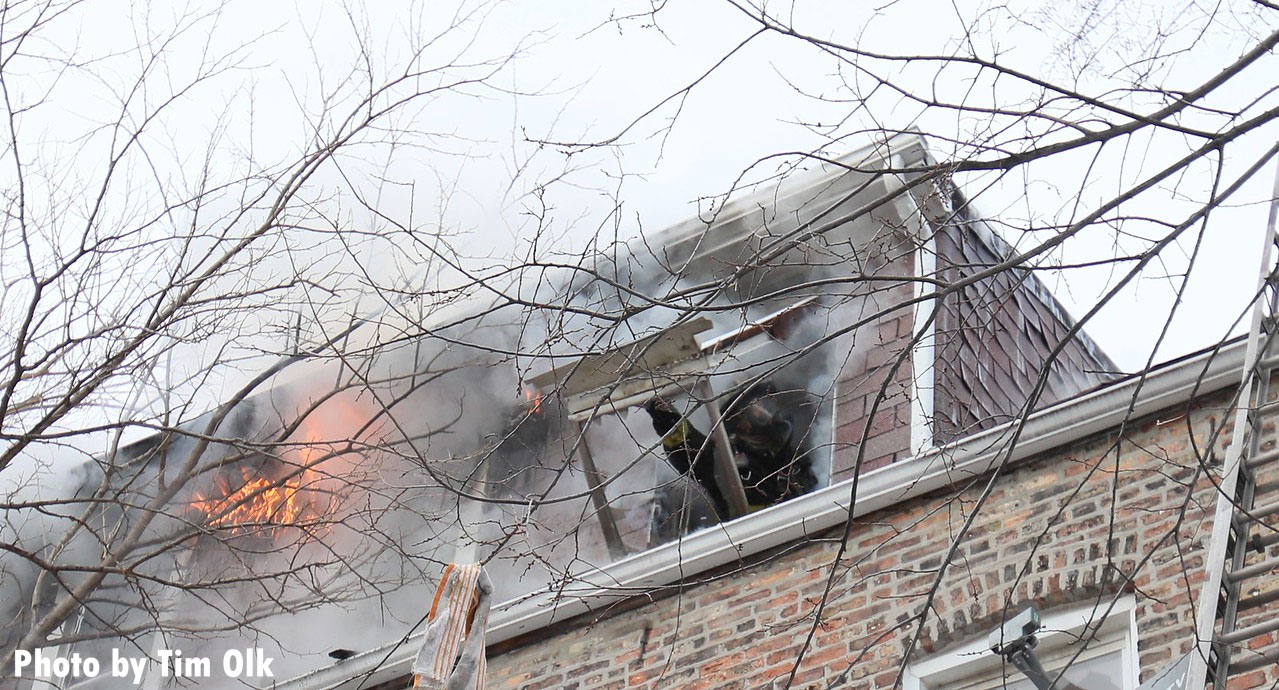 Chicago firefighter knocks out a window as flames shoot out of home