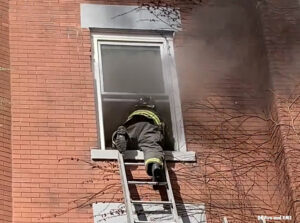 D.C. firefighter on ladder going through window with smoke