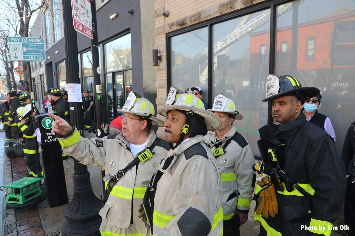 Chicago fire chiefs and firefighters point out details at fire building