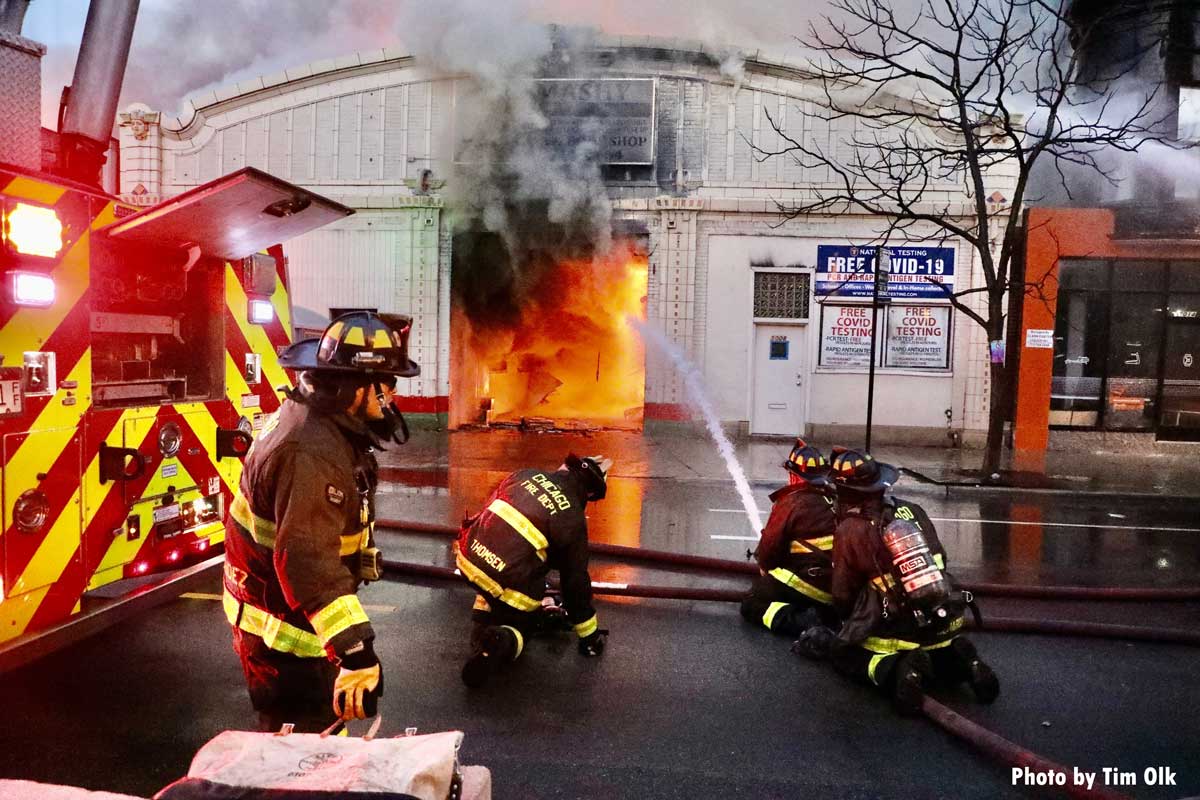 Chicago firefighters put hose stream into open door at auto shop