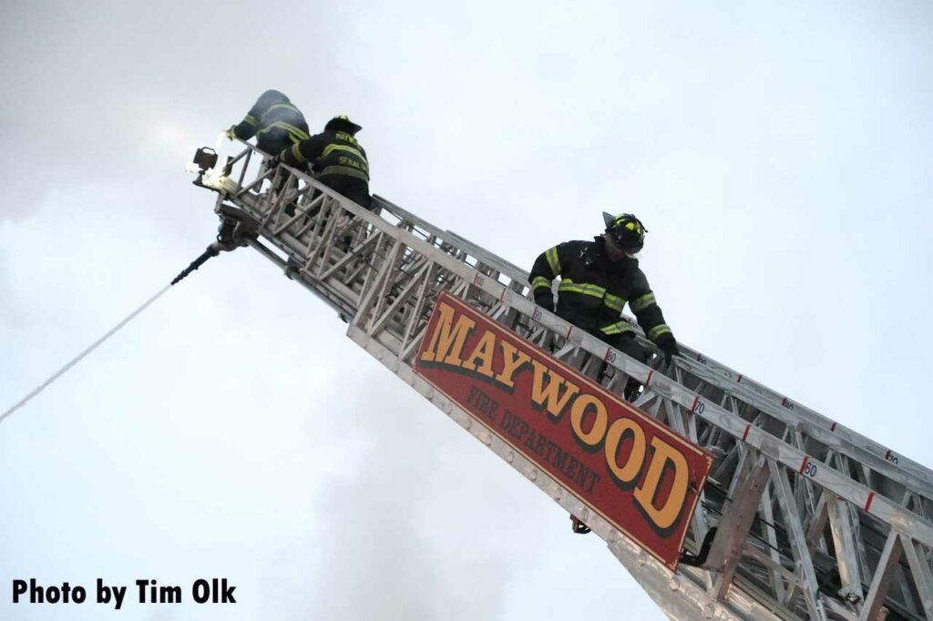 Three firefighters on Maywood aerial ladder