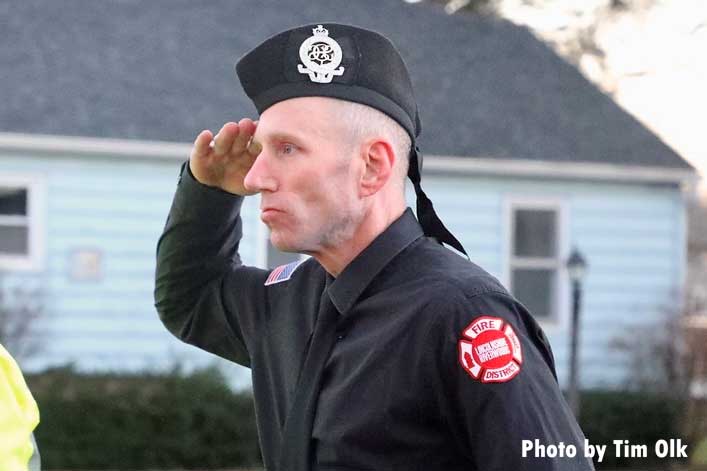 Firefighter salutes during memorial for fire dog