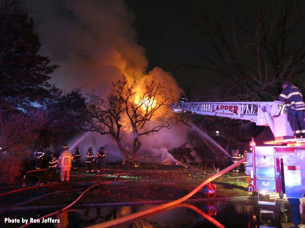 Aerial ladder with master stream and firefighters with streams put water on Ridgefield NJ fire